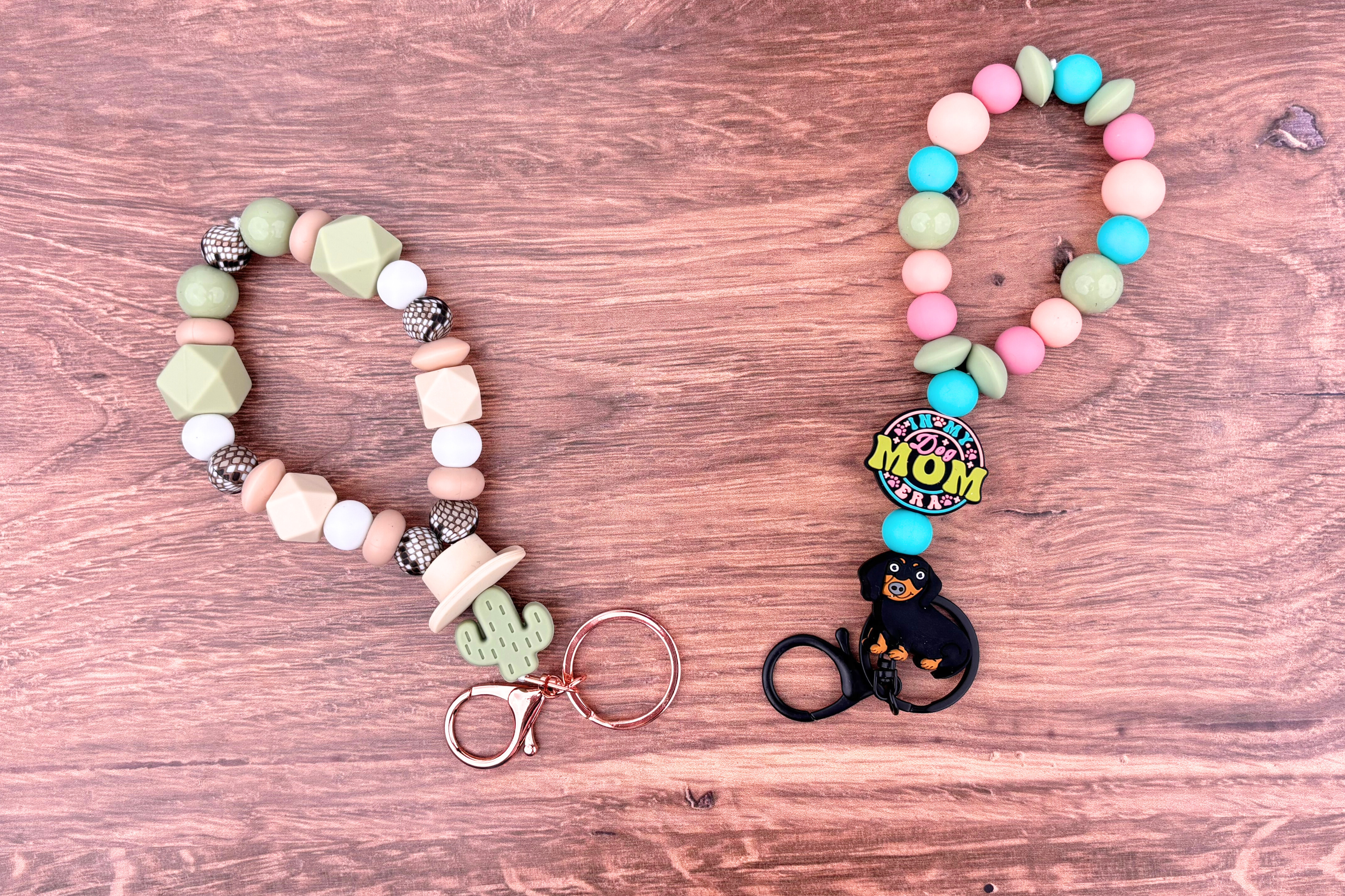 Two finished DIY beaded wristlet keychains in different designs - a dog mom style and a western cactus theme.
