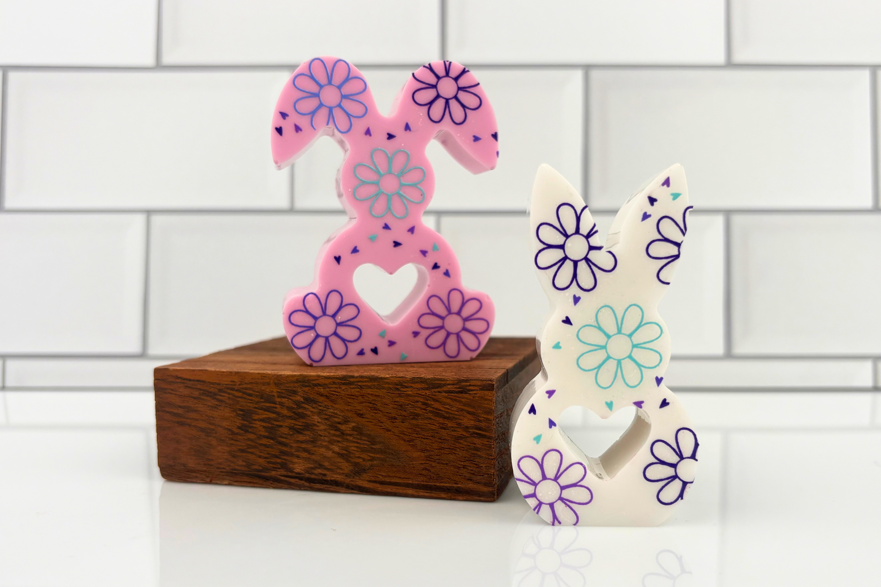 Two finished resin bunnies in pearl finish with floral UV DTF decals applied to their bodies.