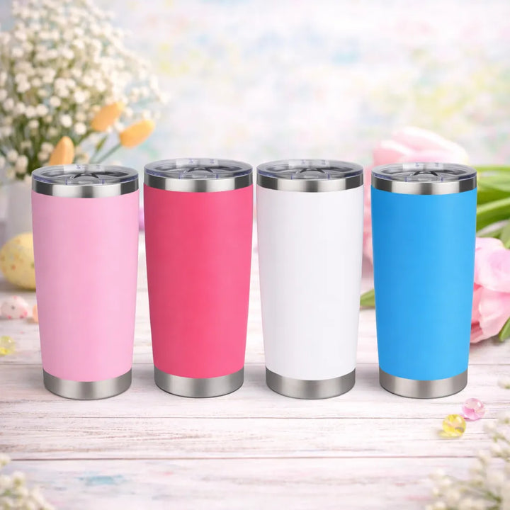 Four insulated tumblers in pink, red, white, and blue on a wooden surface with a floral background.