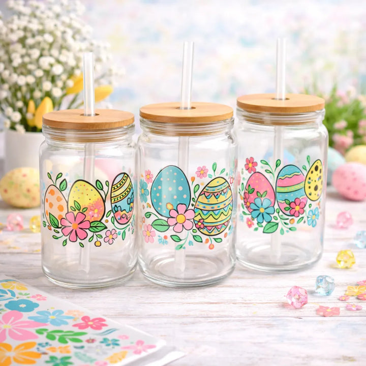 Three glass jars with wooden lids and Easter-themed designs on a decorative surface.