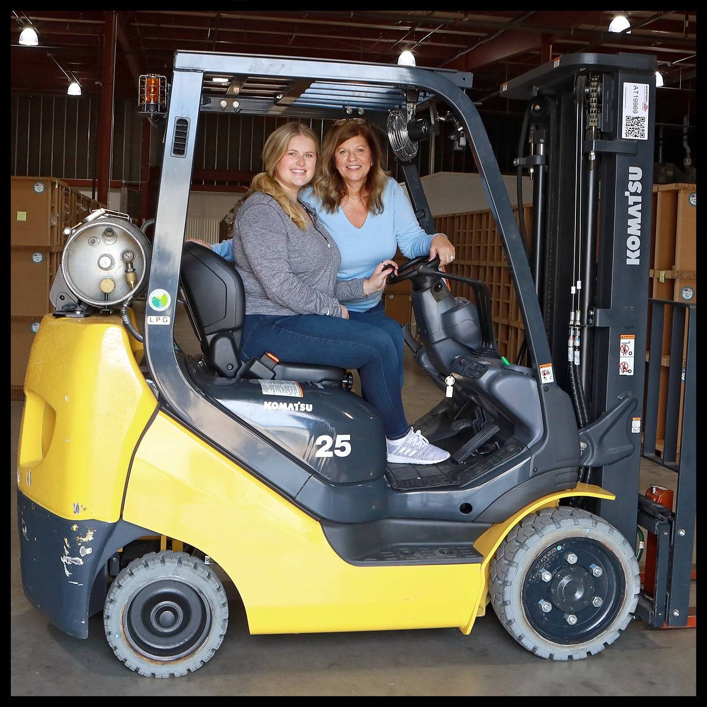 Two women with a forklift in a warehouse, wholesale craft supplies, fast USA shipping.